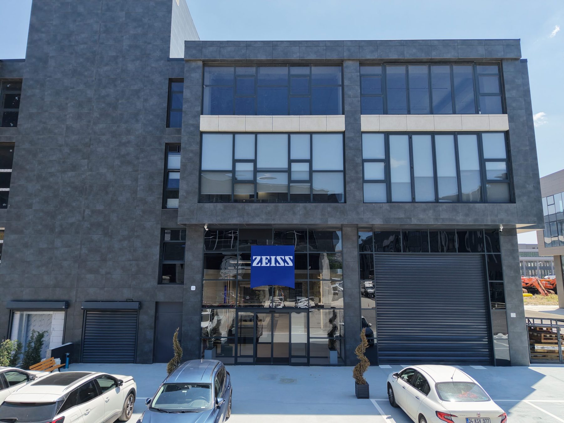 Drone photograph of the three-storey dark stone-clad building with the Zeiss sign over the entrance