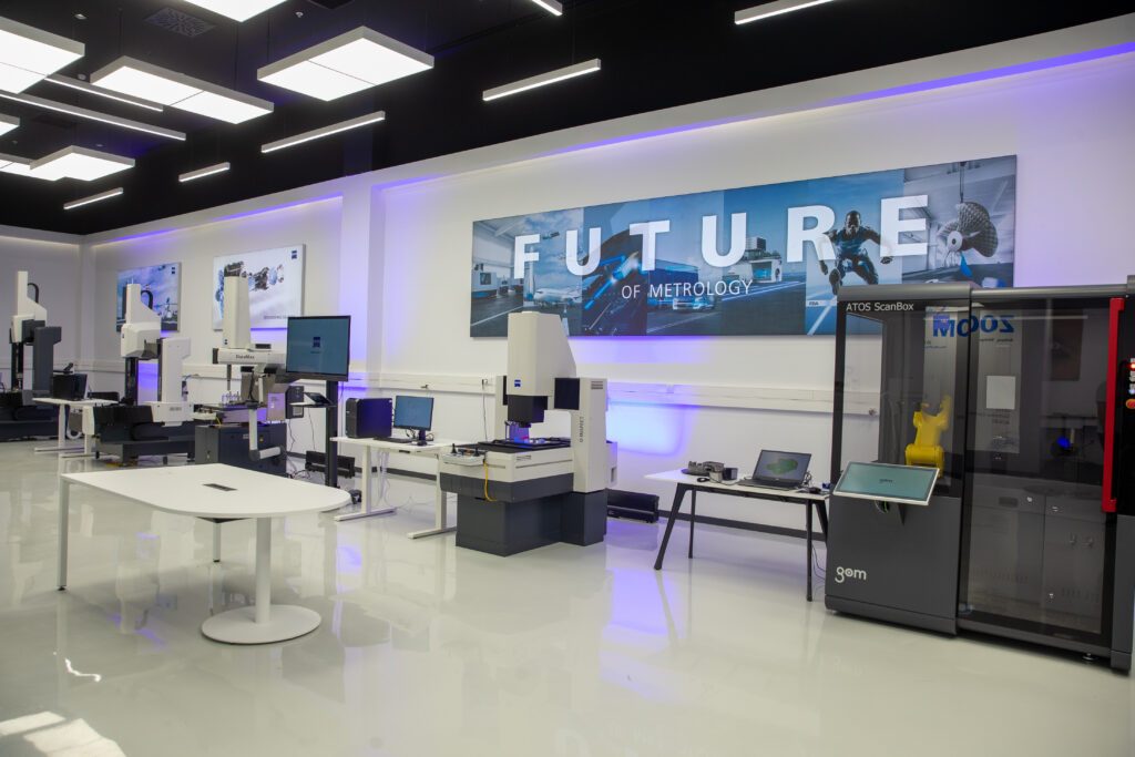 Metrology showroom with coordinate measuring machines on white tables under a dark ceiling with linear lighting